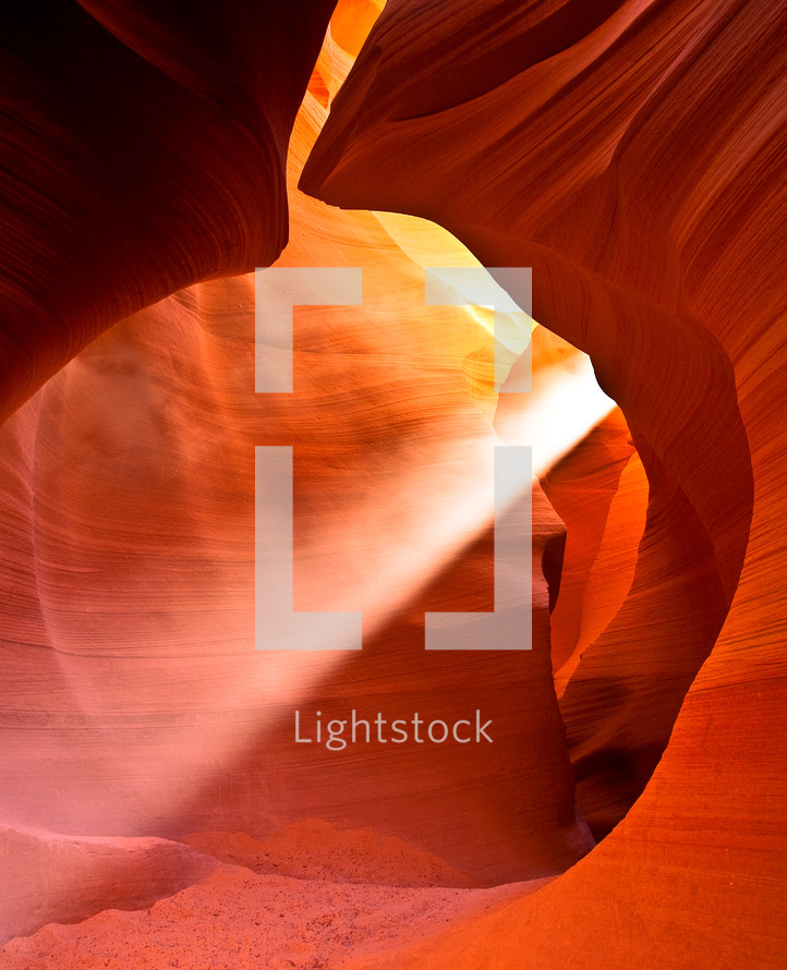 rays of sunlight shining in a red rock cave 