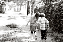 a boy and girl child walking down a path 