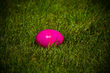 pink plastic Easter egg lying in the grass