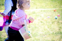 toddler girl holding an Easter basket at an Easter egg hunt