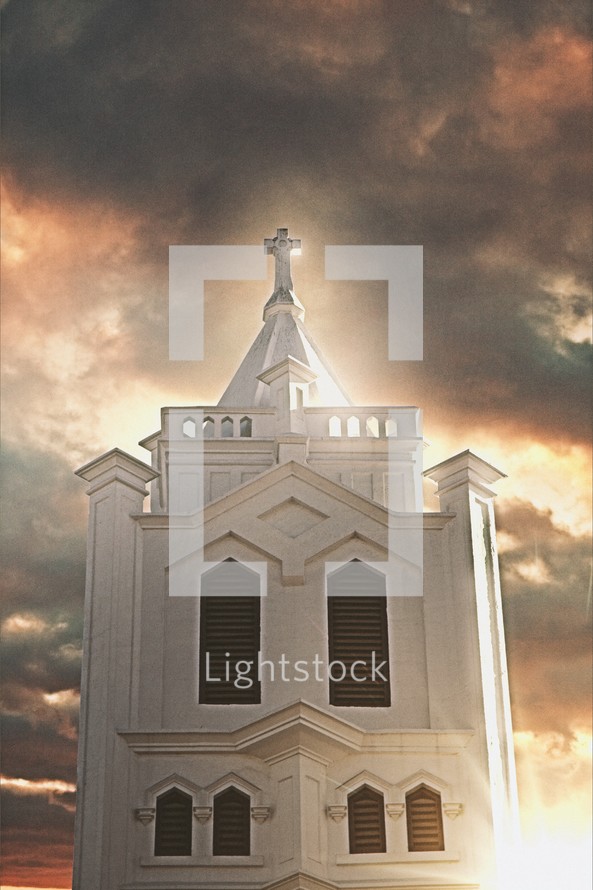 sunlight shining through a cloudy sky on a white church steeple