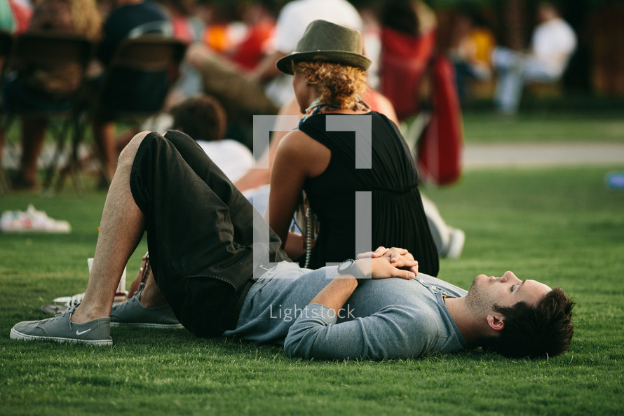 man resting in the grass at an outdoor concert 