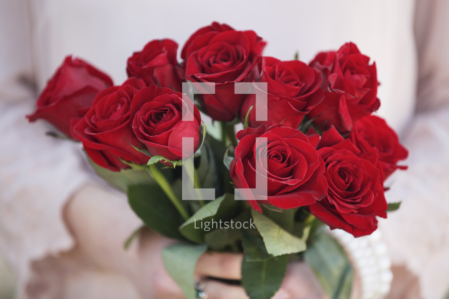 woman holding a bouquet of red roses.