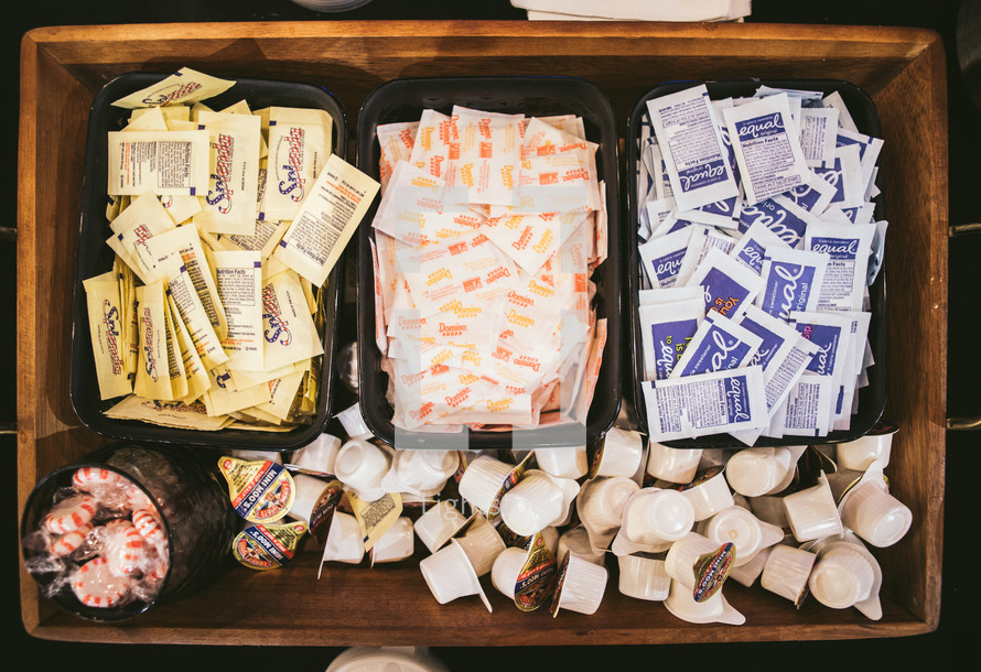 A wooden tray full of condiments for coffee.
