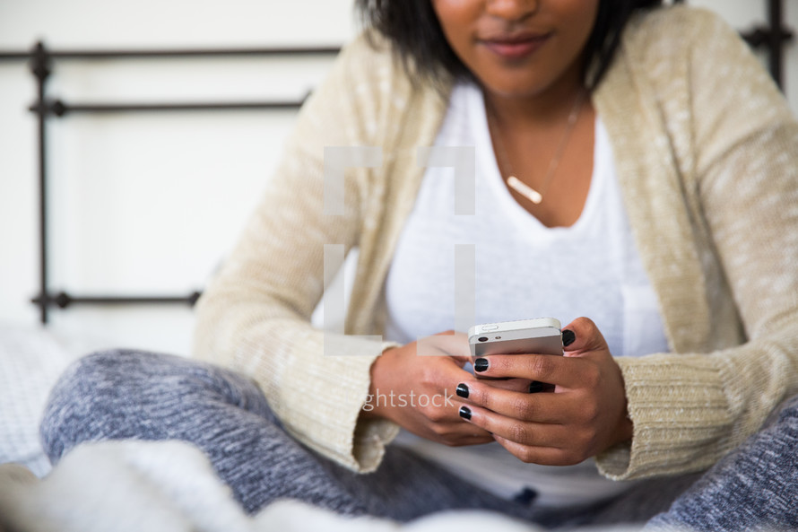 young woman sitting in bed texting 