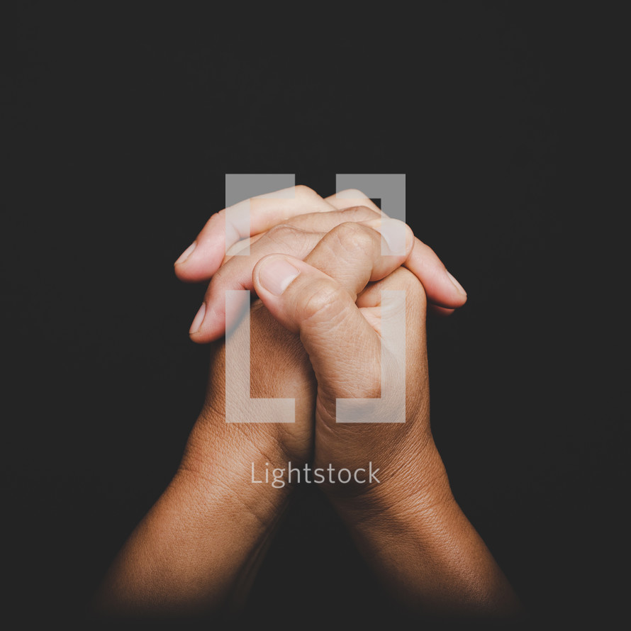Close up of Asian woman's hands folded together in prayer