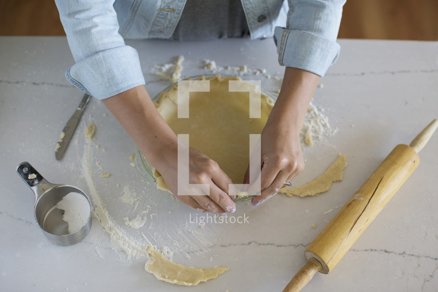 Hands preparing a pie crust for baking.