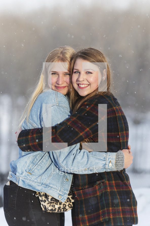 two friends hugging out in snow