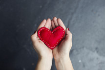 a woman holding a red felt heart 