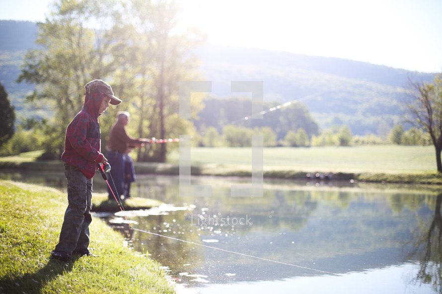 a grandson and grandfather fishing in a pond 