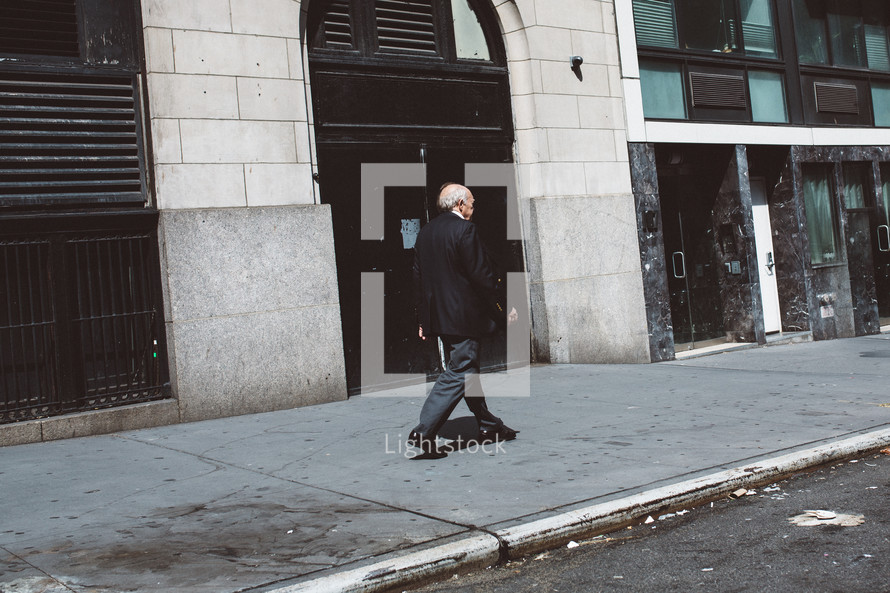 an elderly man walking down a sidewalk 