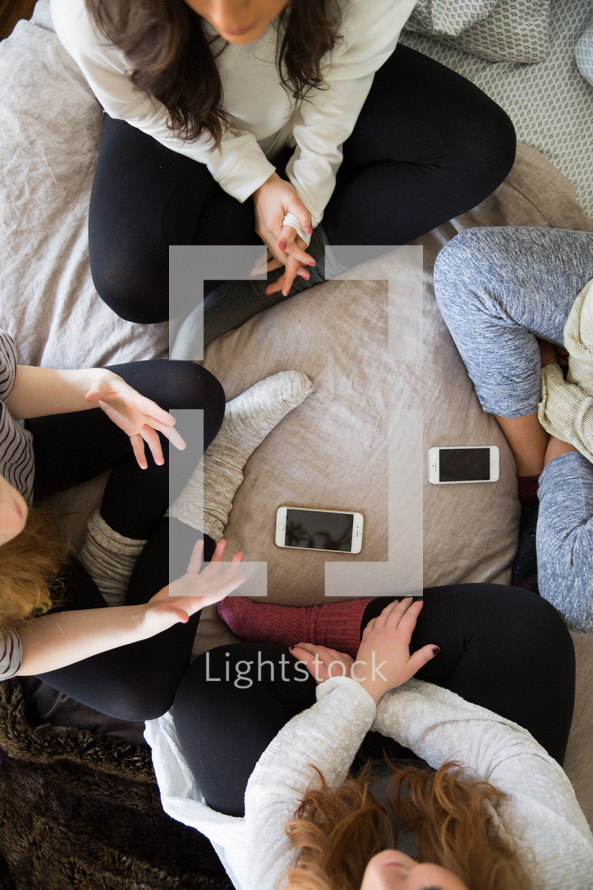 young women sitting on a bed talking 