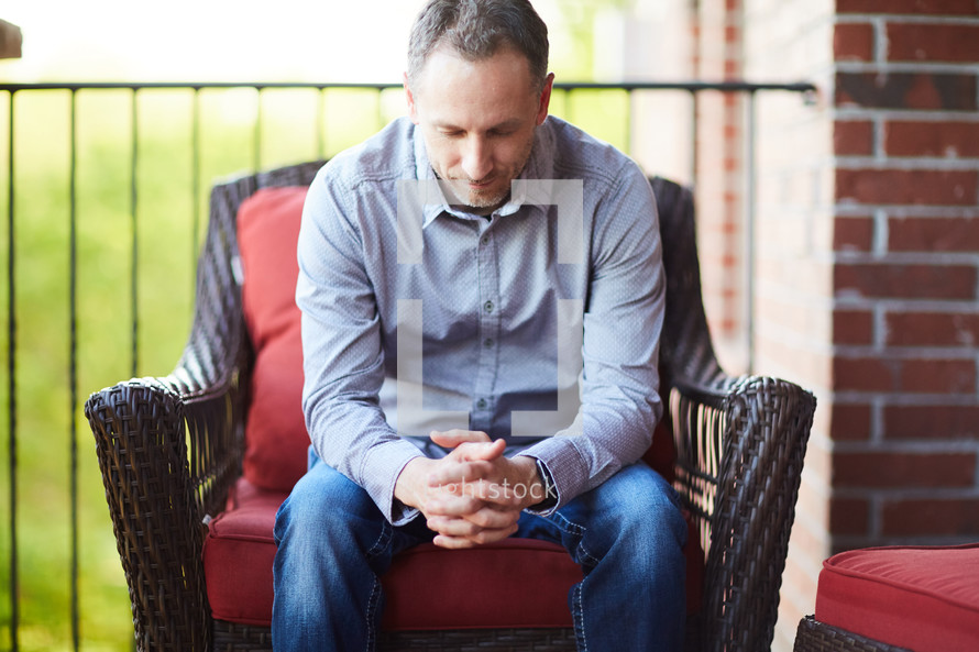 a man sitting on a porch praying 