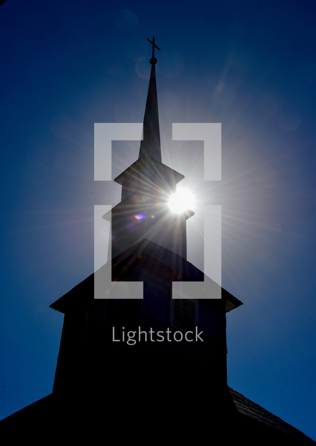 sunburst behind a silhouette of a church steeple 