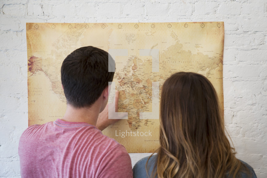 a couple looking at a world map together 