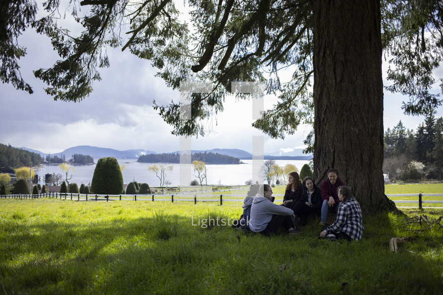 young women sitting under a tree 