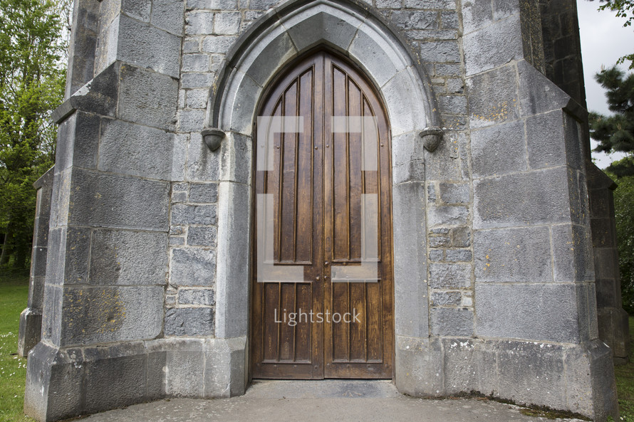 wooden arched door on a stone church 