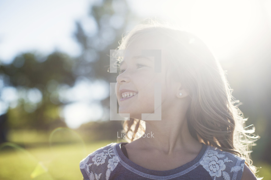 a smiling girl child outdoors in sunlight 