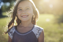 a smiling little girl outside. 