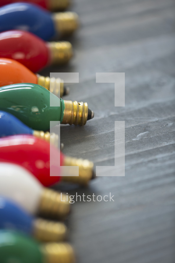 a row of colored lightbulbs on wood 