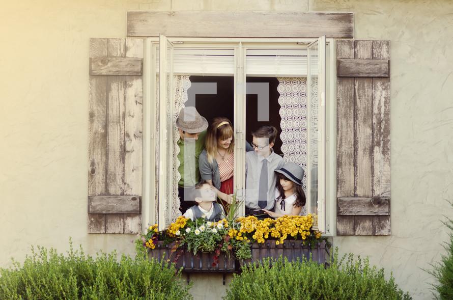 Family in a window with flower boxes.