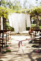 pink ribbon at the front of an aisle at an outdoor wedding ceremony
