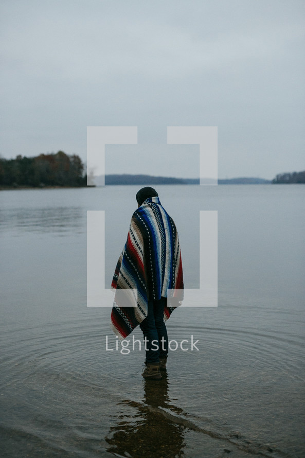 a man wrapped in a blanket standing in water 