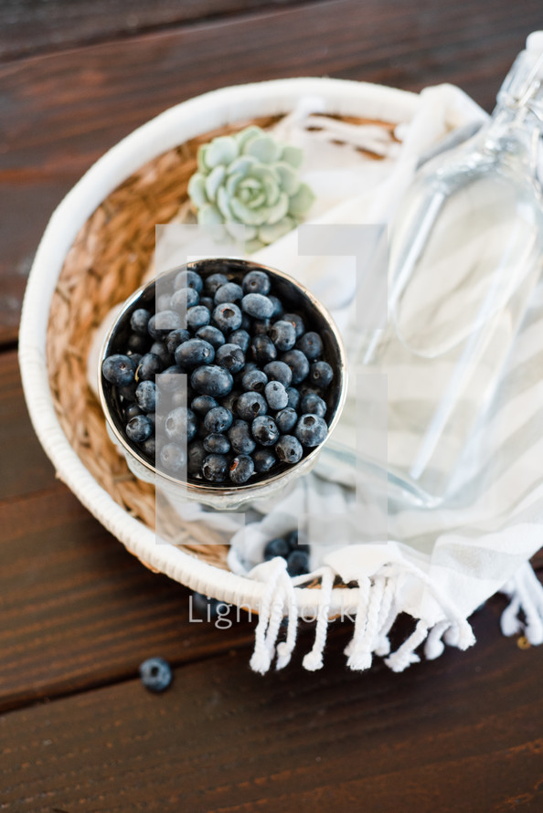 blueberries, basket, succulent plant, glass bottle, blanket, on a table 
