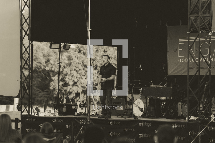 man on stage at an outdoor worship service 