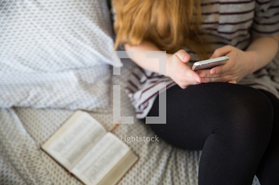 girl texting sitting on a bed