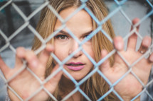 a woman behind a chain link fence 
