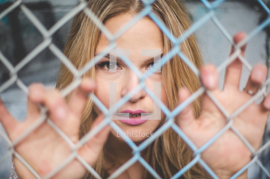a woman behind a chain link fence 