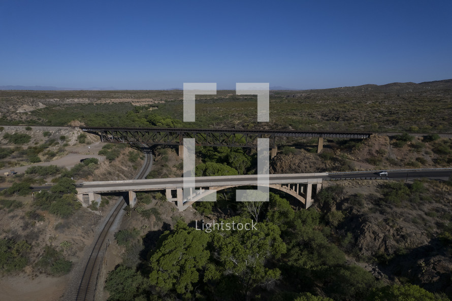 Aerial of a train trestle and highway bridge over a wooded canyon