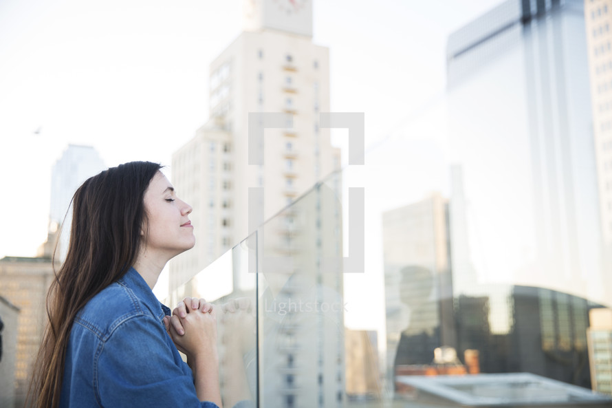 praying woman standing on a rooftop balcony