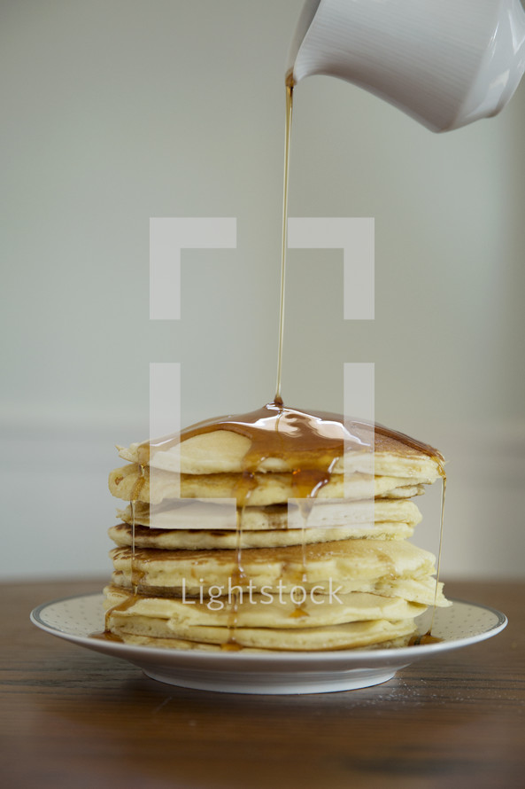 pouring sugar on a stack of pancakes 