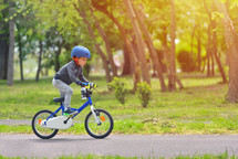 child with a helmet riding a bike at a park 