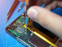 Smartphone technician repairing the motherboard of a smartphone on service lab desk