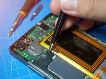 Smartphone technician repairing the motherboard of a smartphone on service lab desk