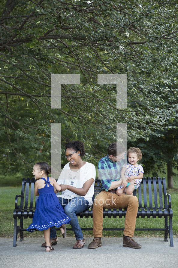 family sitting on a park bench outdoors 