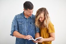 a man and woman standing reading the Bible together 