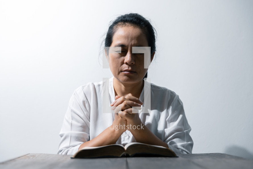 Woman praying with Bible and white background