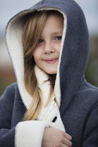 a little girl wrapped up in a coat.