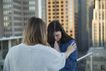 women praying together on a city rooftop 