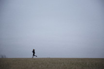 A woman jogging in an open field.