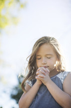 a girl child with praying hands 