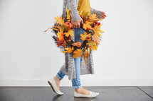 a woman carrying a fall wreath 