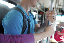 people holding onto a pole riding a city bus.