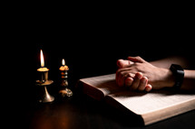 Bible and candlelight with praying hands