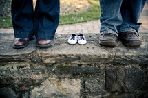 shoes on a man and woman standing next to empty baby shoes