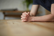 praying hands on a wood table 
